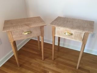 a set of side tables in a light wood with gold finishings