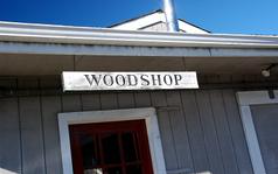 woodshop sign hanging from a building with a red door